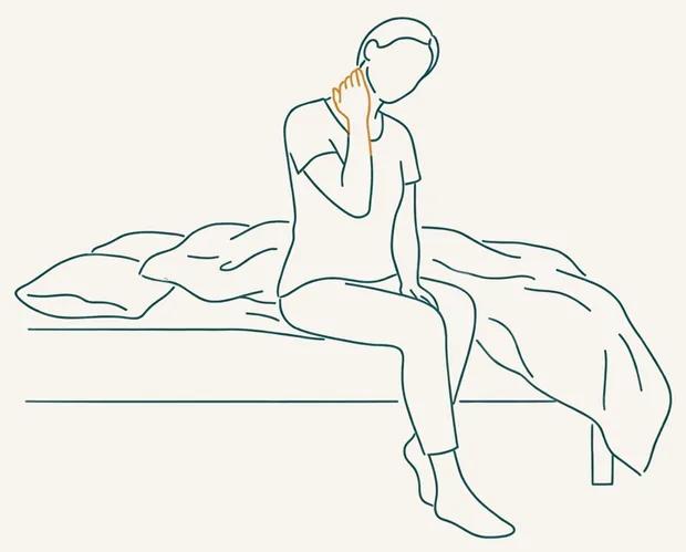 Personne assise au bord du lit, la main sur la nuque au réveil